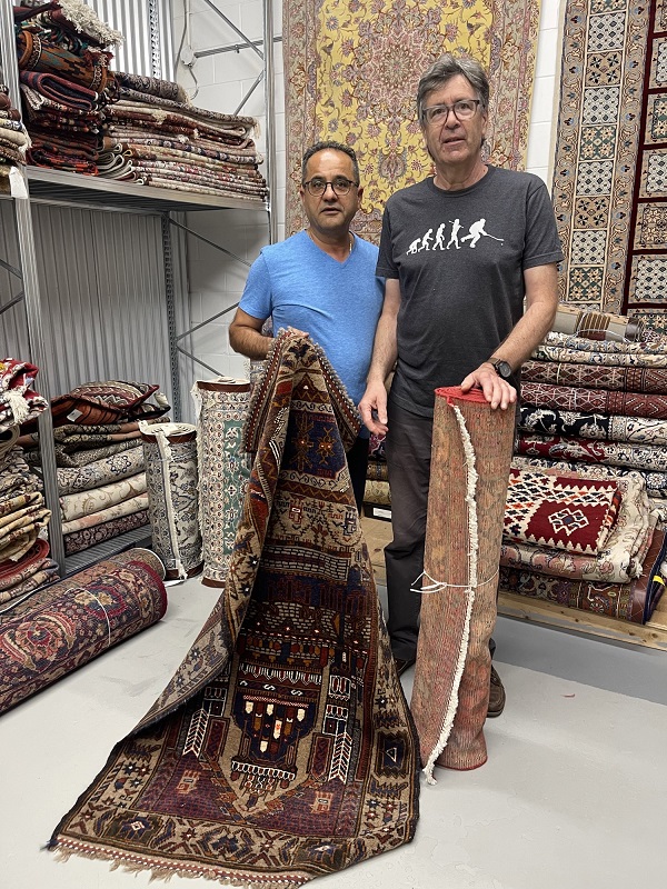 Bob standing with his cleaned and repaired rugs and Hamid